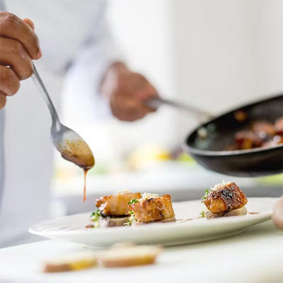 Chefs preparing food in a restaurant kitchen.